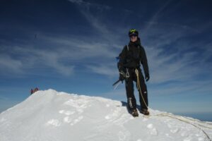 Francis Dumon au sommet d'une arĂªte enneigĂ©e, encordĂ© et en crampons, sous un ciel bleu